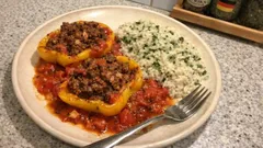Gefüllte Paprika aus dem Ofen: saftig in Tomatensauce, dazu lockerer Kräuterreis